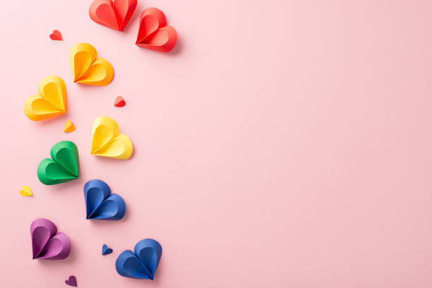 istock A festive display of multi-colored paper hearts in rainbow hues on a pink surface, symbolically representing inclusion and diversity for Pride month 2150688884