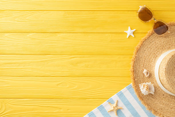 istock Shoreline sanctuary scene: Top view presenting sunhat, sunglasses, beach essentials, blanket, island accessories, seashells, starfish on yellow wooden base, allowing space for marketing purposes 2150688885
