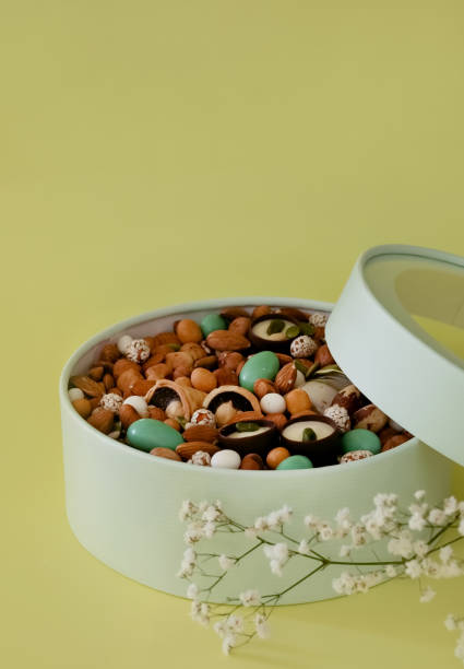 On a light background there is a round box filled with various nuts and dried fruits. Mothers Day. Valentine's Day. International Women's Day.A delightful gift. Low-fat food.
