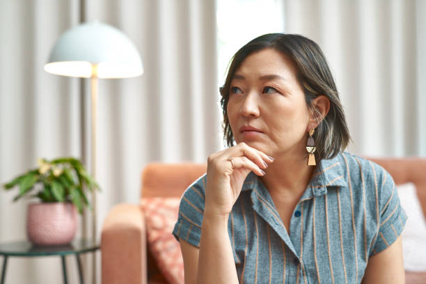 istock Thinking, idea and asian woman in house with calm reflection, remember or memory in her home. Nostalgic, questions and mature Korean person in living room with imagine, fantasy or daydreaming at home 2150692254