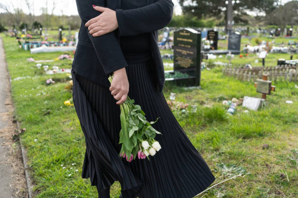 istock Woman carrying flowers at graveyard 2150695717