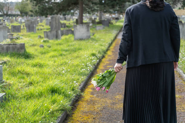 istock Woman at grave carrying flowers 2150695747