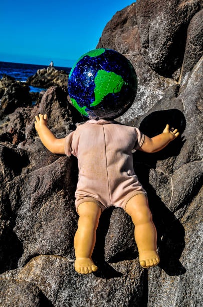 istock A doll is sitting on a rock with a globe on its head 2150695938