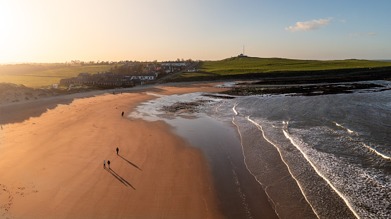 Aerial panorama landscape view of The England Coast Path along Embleton Bay beach at Newton-By-The-Sea village at sunset