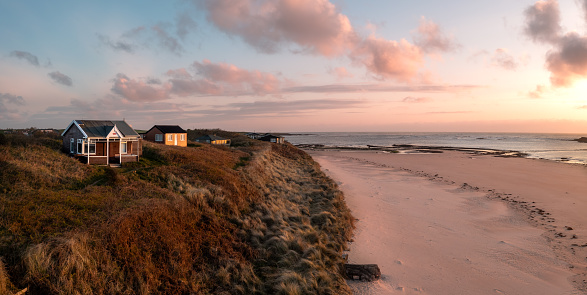 Aerial view of remote beach huts with a sea view on the Northumbrian sand dunes over looking Embleton Bay beach at sunset