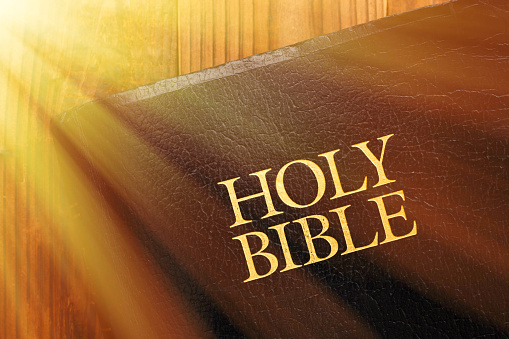 Holy Bible on wood with sun flare