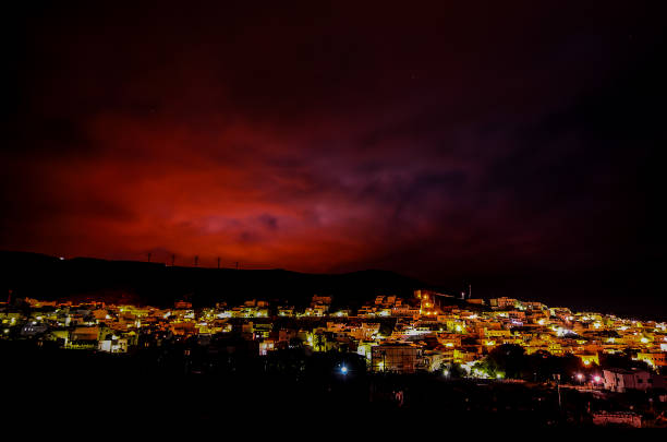 A city at night with a red sky. The city is lit up with lights