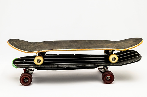 A skateboard is propped up on its side with the wheels facing up. The skateboard is black and white and he is old