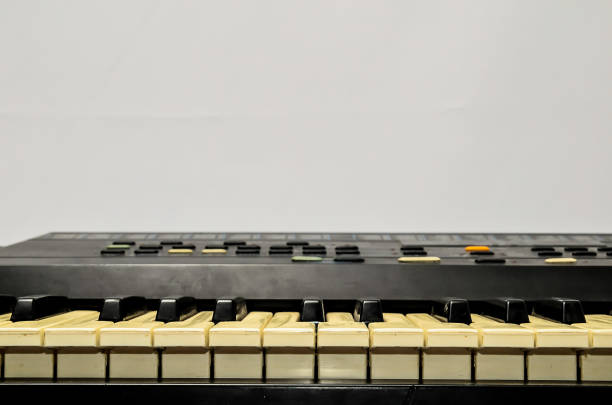 A black and white keyboard with white keys. The keyboard is old and has a vintage look