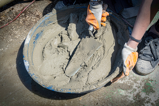 A woman mixes cement and water.