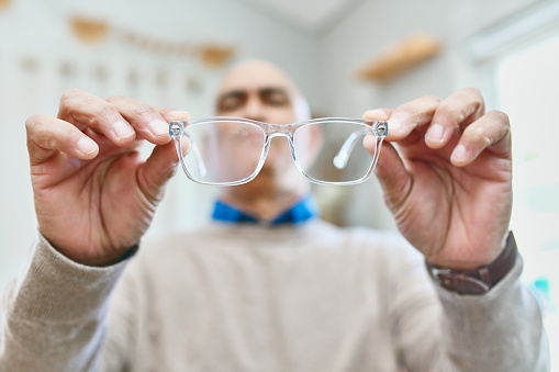 Senior, man and glasses in hands, home and vision for eyes, health and optometry for eyecare. House, frame and eyewear for elderly person, retirement and eyesight with lens, prescription and grandpa