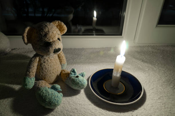 istock Teddy bear in the dark next to a burning candle 2150702905