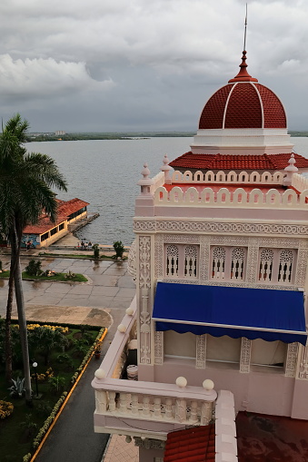 Cienfuegos, Cuba-October 11, 2019: Palacio de Valle, eastward view over the rooftop pavilion and northeast turret to the east bay under stormy sky at late afternoon after a heavy tropical rain.