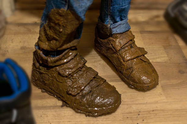 Close-up of feet in boy's muddy boots, standing guiltily in hallway Close-up of feet in boy's muddy boots, standing guiltily in hallway. kids dirty shoes stock pictures, royalty-free photos & images