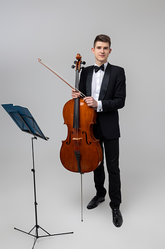 Full length of young male musician performing with cello and music note isolated over white background
