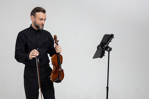 Handsome man holding a violin in his hands playing classic music isolated over white background