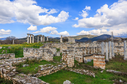 Beneath a lively sky, the remnants of walls and columns in Afrodisias narrate a story of antiquity, with the tranquility of the surrounding hills offering a silent audience to history's whispers.