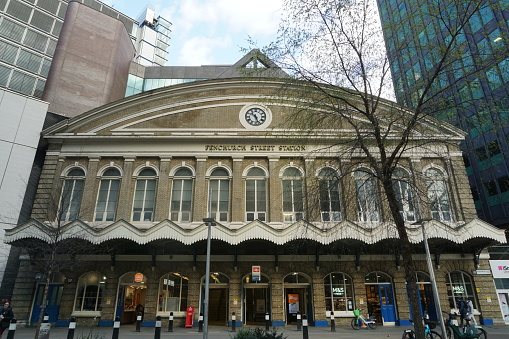 London, England - 20 April 2024: The 19th century facade of Fenchurch Street station  contrasts with the surrounding office blocks. The station is well known for it's inclusion on the UK version of the Monopoly board game.