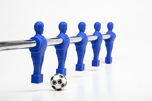 Foosball figures poised to kick the ball, (table soccer or table football)  on white background