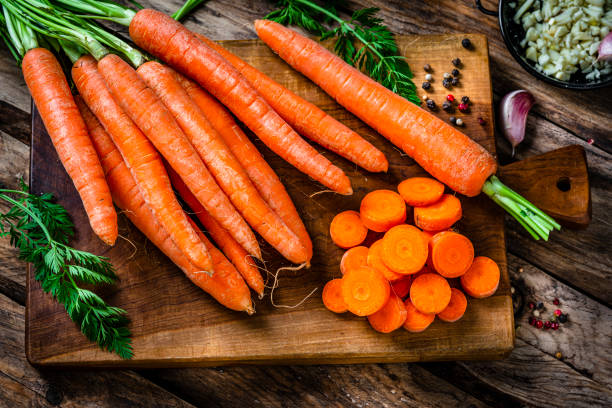 Overhead view of freshly sliced organic carrots on cutting board Overhead view of freshly sliced organic carrots on cutting board. High resolution 42Mp studio digital capture taken with Sony A7rII and Sony FE 90mm f2.8 macro G OSS lens pile of carrots stock pictures, royalty-free photos & images