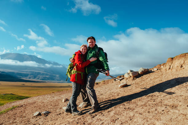 Young woman with curly hair and backpack smiling and enjoying mountain landscape, embracing mindful travel and healthy lifestyle
