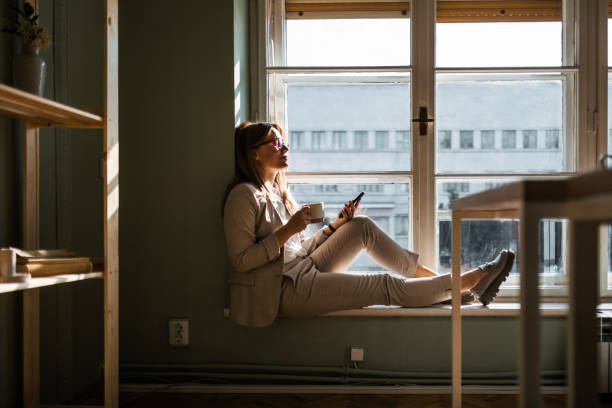 istock Businesswoman Managing Tasks on Phone by Window 2150716233