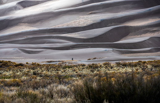 A hiker walks along the bottom of sand dunes at the Great Sand Dunes National Park near Mosca, Colorado. The park covers over 149,000 acres of land and is home to the tallest sand dunes in North America. The sand dunes in the park were formed over thousands of years as winds blew sand from the nearby San Luis Valley and deposited it in the park.