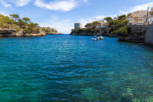 Cala Figuera, Spain -April 20, 2024: Beautiful view in the small picturesque bay of Cala Figuera and in the far with some tourists. This scenic harbor is situated in the southeast of Mallorca attracting thousend tourists annually.