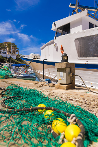Cala Figuera, Spain -April 20, 2024: Part of the Cala Figuera fishing harbor, featuring a large fishing boat with nets. Nestled in a charming little bay, this idyllic harbor is a famed tourist spot in southeastern Mallorca.