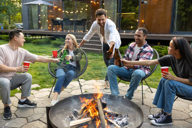 istock Cheerful multicultural friends sitting near fire on backyard enjoying happy weekend 2150723424