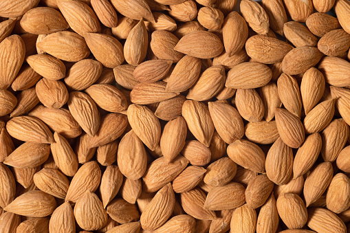 Background of raw almonds for background or textures. Unshelled almonds in shell.