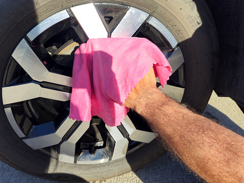 man cleaning dirty car wheel
