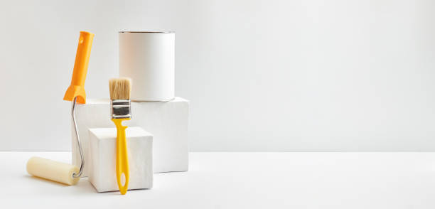 Geometric podium or pedestal with paint can, brush, sponge roller on a white background. Mock up for displaying works