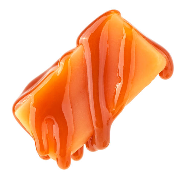 istock Caramel sauce flowing on caramel candy, isolated on a white background. Levitating caramel candy. 2150732106