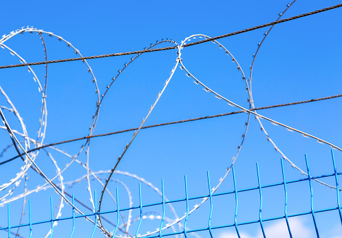 Barbed wire against the blue sky background. Protective fencing specially protected object of barbed wire