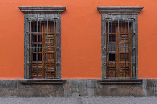 Two windows on a building with a wooden frame