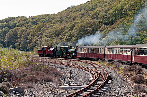 View of a steam locomotives, North Wales, going from Porthmadog to Blaenau Ffestiniog, UK.  People can be seen on the steam engine and in the carriages.