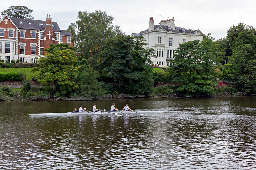 View of people on a rowing boat on the river dee in the centre of Chester, UK.