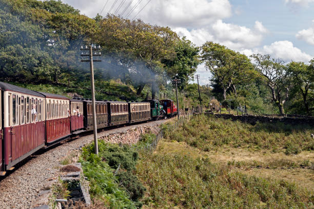 View of a steam locomotives, North Wales, going from Porthmadog to Blaenau Ffestiniog, UK.  People can be seen on the steam engine and in the carriages.
