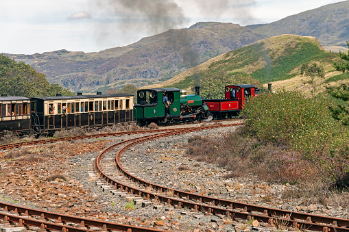 View of a steam locomotives, North Wales, going from Porthmadog to Blaenau Ffestiniog, UK.  People can be seen on the steam engine and in the carriages.