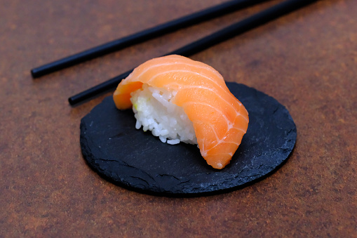 Salmon nigiri sushi on black slate.