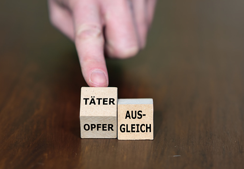 Wooden cubes form the German expression 'Taeter Opfer Ausgleich' (victim-offender compensation).