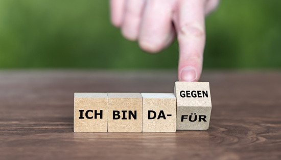 Hand turns cube and changes the German expression ' ich bin dafür' (I am in favor) to 'ich bin dagegen' (I am against it)