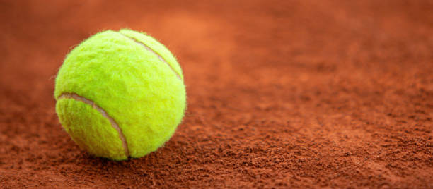 istock Tennis ball on clay court with copy space (8k wide image) 2150738295