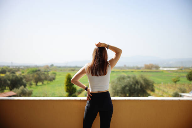 Young fitness woman practicing yoga poses at the baclcony in the morning. Slim girl doing morning yoga routine