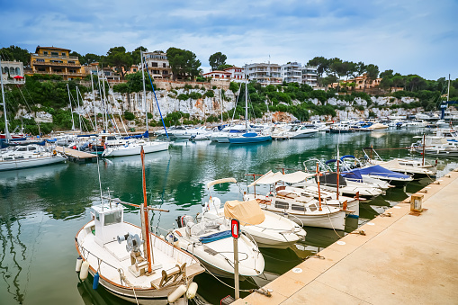 A serene view of the Porto Cristo harbor in Mallorca, showcasing moored boats and the surrounding landscape