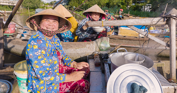 Vietnamese woman selling famous pho bo -noodle soup, floating market on Mekong River Delta, South Vietnam. Pho bo is a extremely popular Vietnamese noodle soup consisting of broth, rice noodles, herbs and beef meat.
