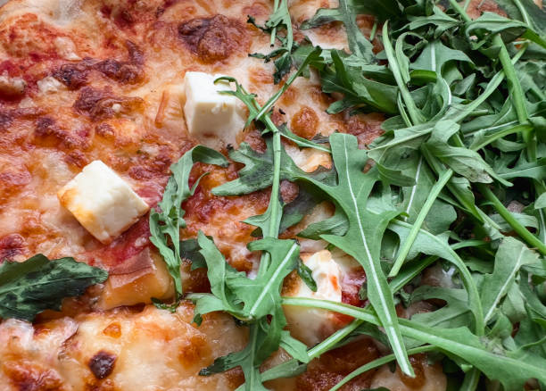 A pizza with cheese and spinach on top.