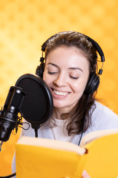 istock Happy narrator wearing headphones reading aloud from book into mic 2150744998