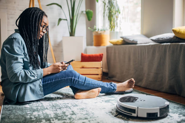 istock Woman sitting on floor with robot vacuum 2150745134
